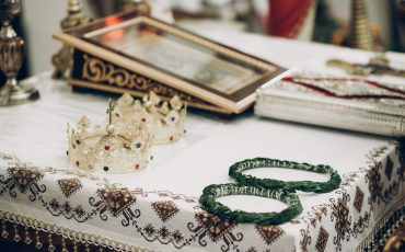 golden crowns and green wreaths on altar in church during wedding ceremony